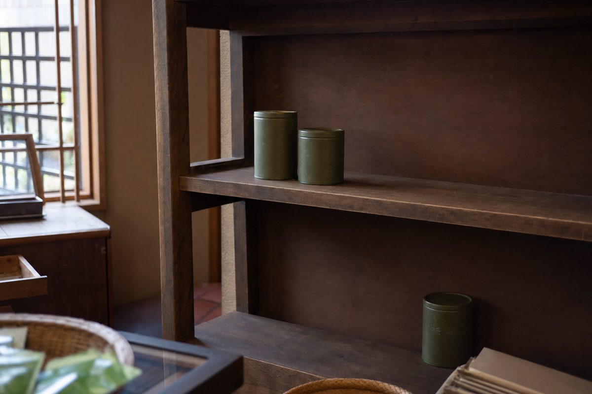 A nearly empty wooden shelf in a Japanese tea shop, with only a few tins left